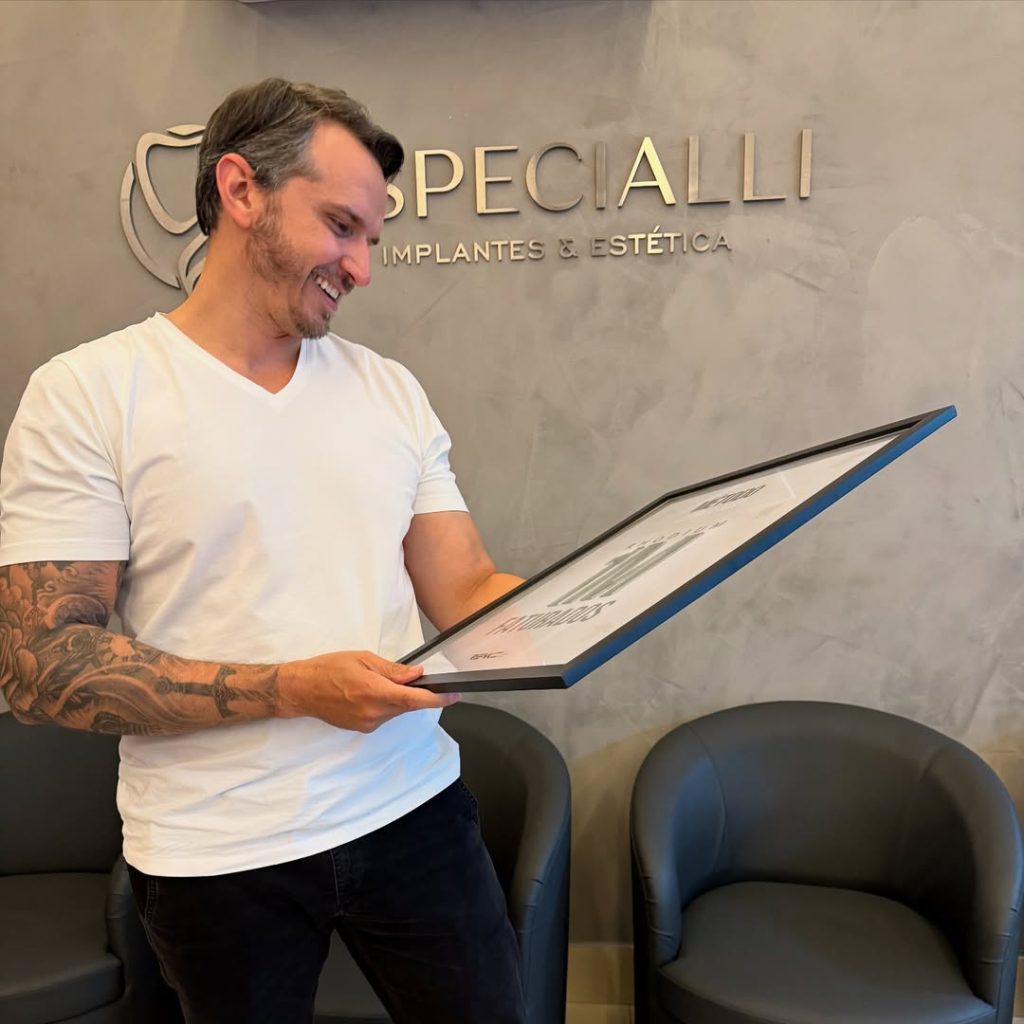 médico gestor de clínica segurando placa de conquista de receita anual com sorriso orgulhoso na recepção da clínica premium